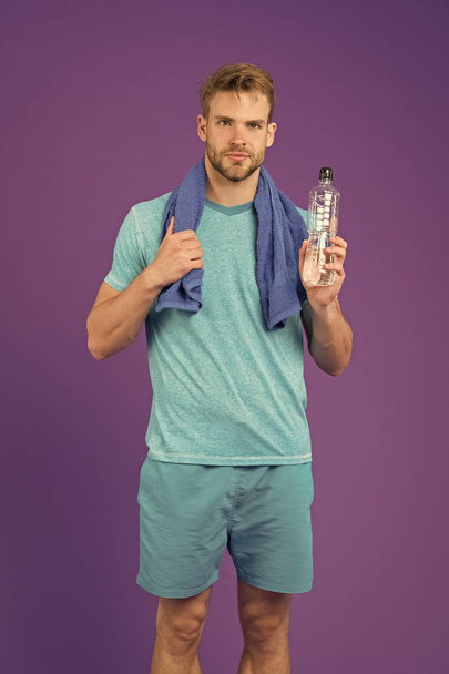 Stay hydrated. Man with towel on shoulders hold bottle. Athlete drink hydration mix with more electrolytes. Hydrates faster than water alone with an optimal ratio of carbohydrates. Keep you hydrated - Zdjęcie, obraz