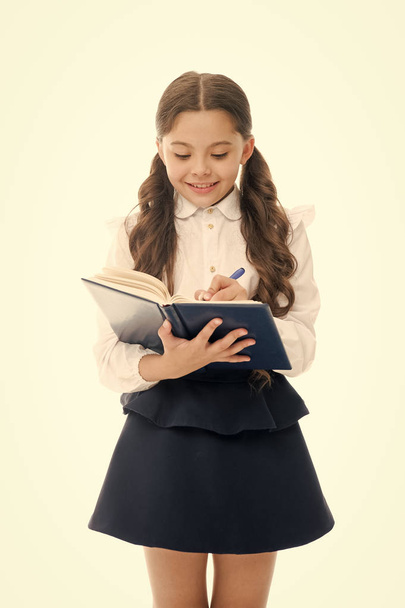 Schoolgirl write daily schedule notepad isolated on white. Little child hold textbook with pen. Plan for week. Home schooling education. Adorable bookworm planning her studying schedule for week - Photo, Image