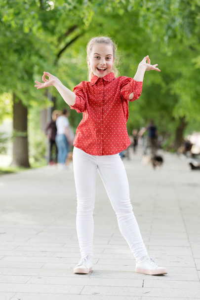 Summer holidays. Emotional kid in park nature background. Charming stylish fashionable girl in park. Little child enjoy walk in park. Weekend walk. Girl carefree child. Kid walking sunny day - 写真・画像