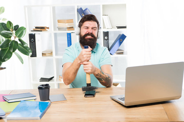 Spoiled communication. Failed mobile negotiations. Most annoying thing about work in call center. Incoming call. Stressful job at call center. Man bearded guy headphones office hammer smartphone - Foto, Bild