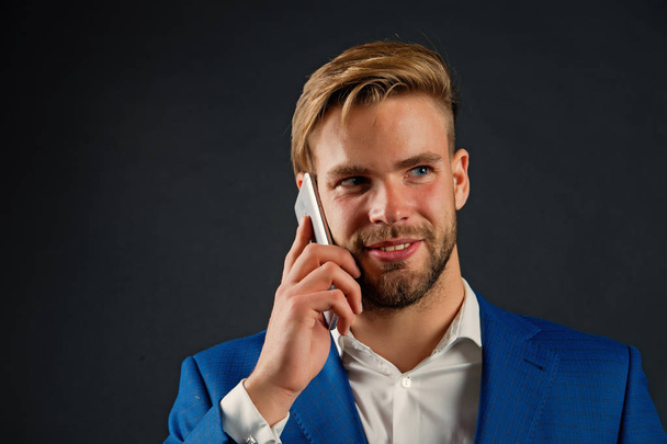 Businessman happy smiling use smartphone communication, black background. Man talk cell phone office. Man in suit businessman takes advantages of modern mobile technologies. Business call concept - Photo, Image