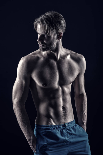 Macho show muscular torso in blue shorts - Foto, Imagen