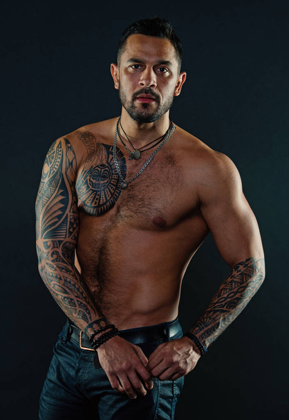 Bearded man with tattooed body. Macho with sexy bare torso in jeans. Tattoo model with six pack and ab. Athlete or sportsman with muscular chest and belly. Sport or fitness and bodycare - Foto, immagini