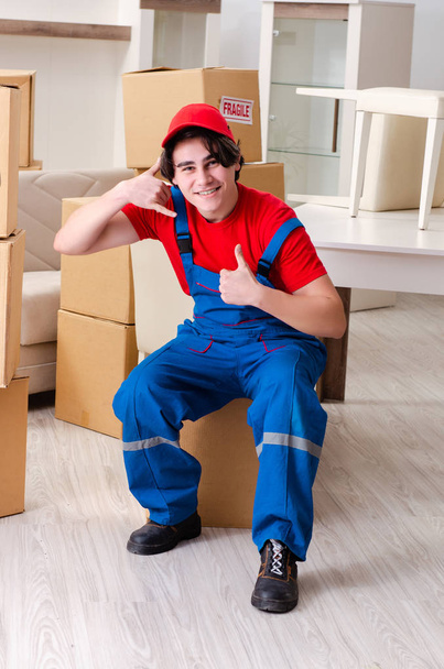 Joven contratista masculino con cajas trabajando en interiores  - Foto, imagen