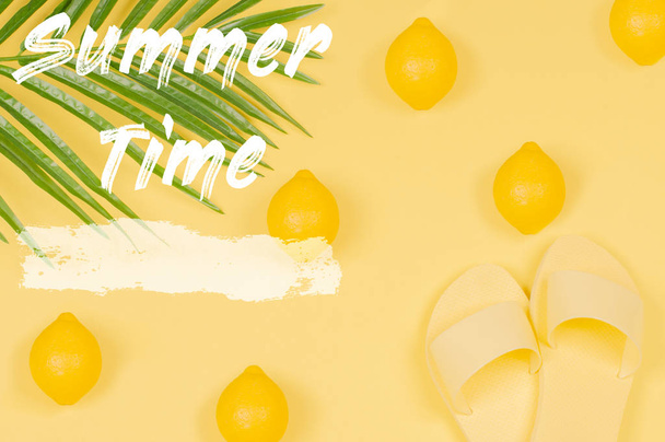 Summer Time text on yellow background with lemon, sandals and green tropical palm leaf. - Φωτογραφία, εικόνα
