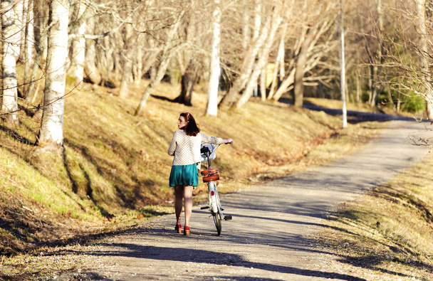 Girl walking with a bike in the park - 写真・画像