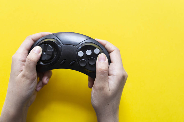 Male hand holds a joystick for video games on a yellow background. Gamepad in the mans hand on a yellow background - Fotó, kép