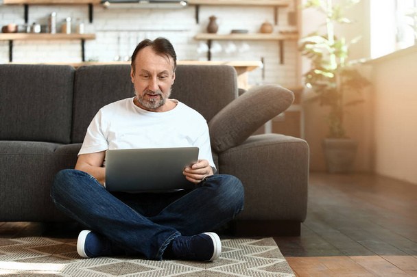 Красивый зрелый мужчина использует ноутбук дома
 - Фото, изображение