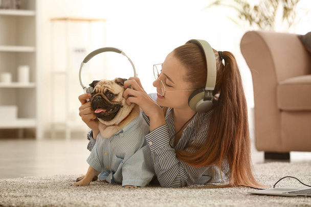 Teenage girl with cute pug dog listening to music at home - Zdjęcie, obraz