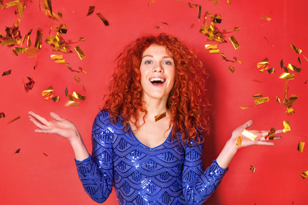 Beautiful redhead woman and falling confetti on color background - Фото, изображение