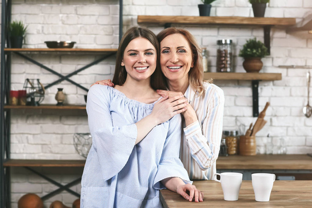 Happy mother and daughter in kitchen at home - Фото, изображение