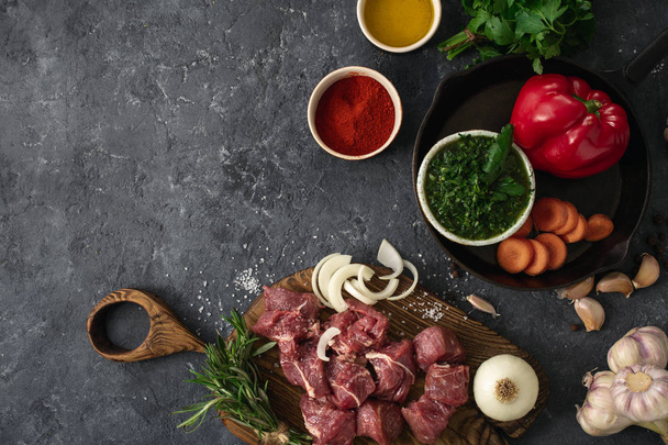 Ingredients for cooking meat with vegetables on a dark background top view. Preparation beef meat - Фото, зображення