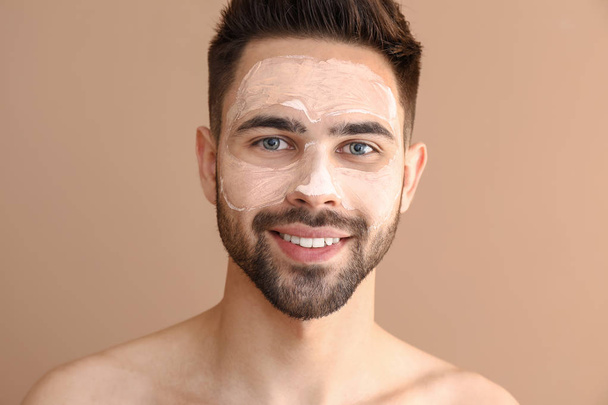 Schöner Mann mit Tonmaske im Gesicht vor farbigem Hintergrund - Foto, Bild