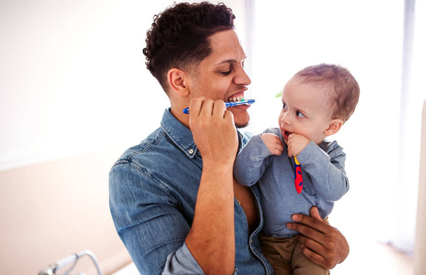 Father and small toddler son in a bathroom indoors at home, brushing teeth. - Фото, зображення