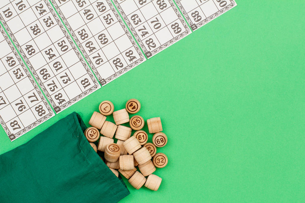 Wooden lotto barrels with bag and game cards on green background - Fotografie, Obrázek