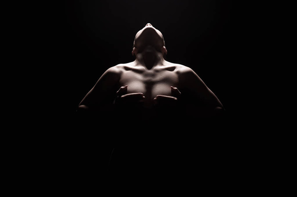 Силуэт обнаженной женщины под светом в темноте
 - Фото, изображение