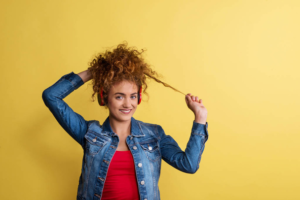 Portrait of a young woman with headphones in a studio on a yellow background. - Foto, afbeelding