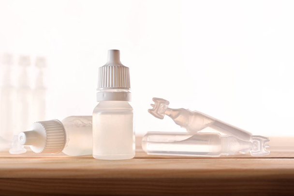 Plastic bottle and pipettes with eye medication on wooden table - Foto, imagen