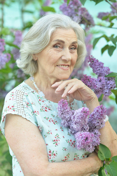 happy  senior beautiful woman with lilacs in spring  park - Foto, afbeelding