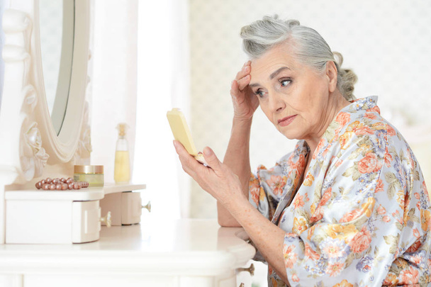 Senior woman applying makeup - Foto, afbeelding