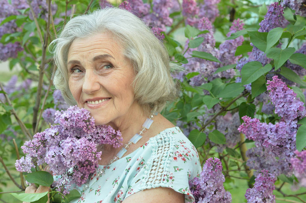 happy  senior beautiful woman with lilacs in spring  park - 写真・画像