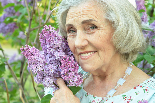 happy  senior beautiful woman with lilacs in spring  park - Fotografie, Obrázek