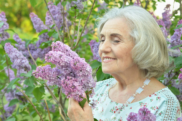 happy  senior beautiful woman with lilacs in spring  park - Фото, зображення