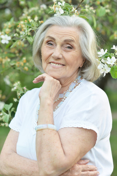 happy  senior beautiful woman in spring  park with blooming apple tree background - Foto, Imagen
