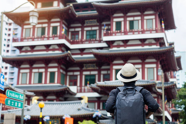 άνθρωπος χίπστερ Ταξιδεύοντας με σακίδιο και καπέλο, Solo ταξιδευτής ψάχνει για τον Βούδα δόντι κειμήλιο ναό στην Τσάιναταουν της Σιγκαπούρης. ορόσημο και δημοφιλές για τα τουριστικά αξιοθέατα. Νοτιοανατολική Ασία ιδέα ταξιδιού - Φωτογραφία, εικόνα