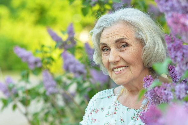 happy  senior beautiful woman on  lilacs background  in spring  park - Foto, afbeelding
