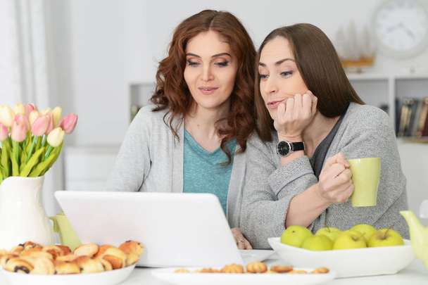two young women using laptop and drinking tea - Foto, Bild