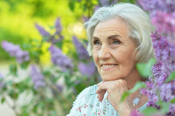 happy  senior beautiful woman on  lilacs background  in spring  park - Zdjęcie, obraz