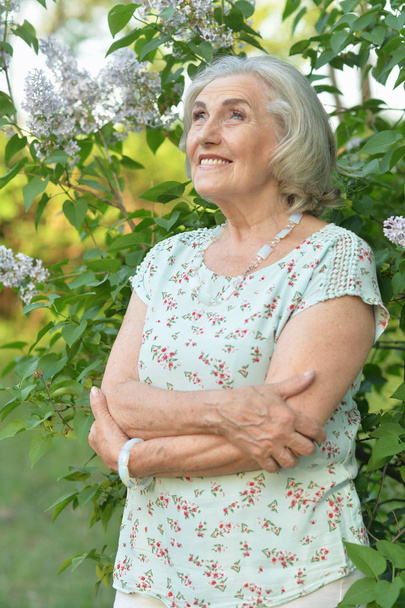 happy  senior beautiful woman on  lilacs background  in spring  park - 写真・画像
