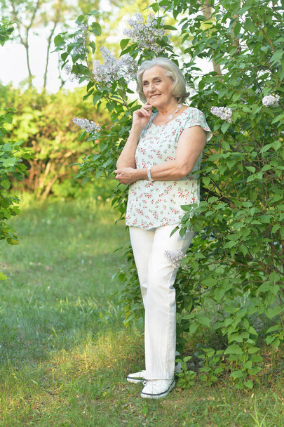 happy  senior beautiful woman on  lilacs background  in spring  park - Фото, изображение