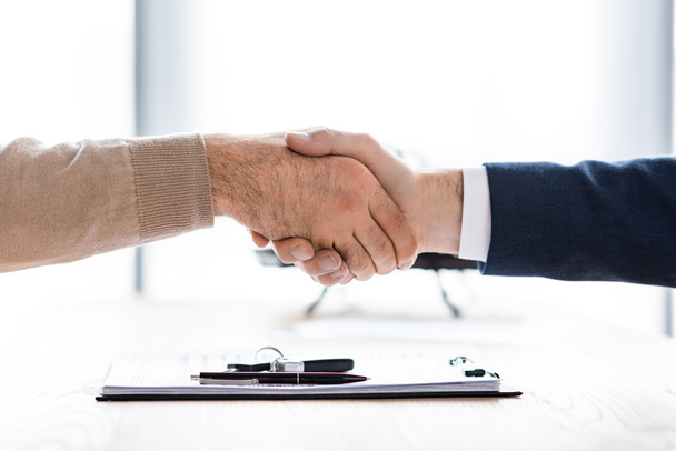 cropped view of man and car dealer shaking hands in office  - Photo, Image