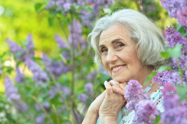 happy  senior beautiful woman on  lilacs background  in spring  park - Foto, Imagen