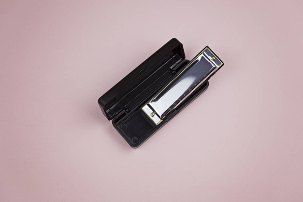 Harmonica in container on a pink background - Φωτογραφία, εικόνα