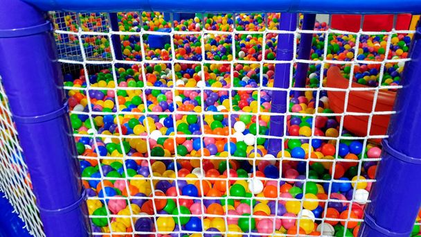 Imagem de close-up de grande piscina cheia de bola de plástico colorido no parque infantil cercado com rede para a segurança das crianças
 - Foto, Imagem