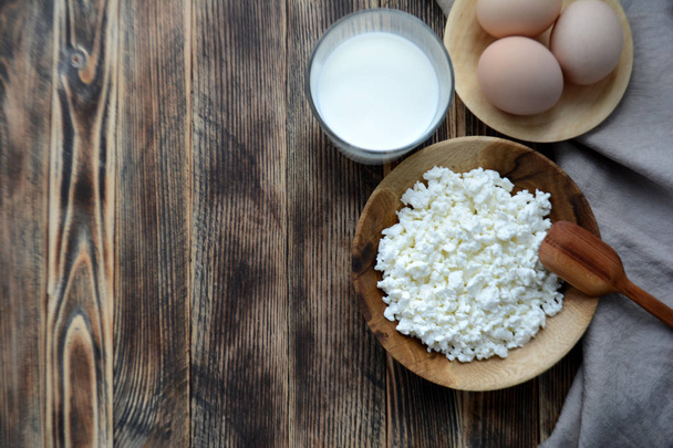 Cottage cheese in a wooden bowl, milk in a glass, eggs. Farm products. Village Breakfast - Фото, изображение