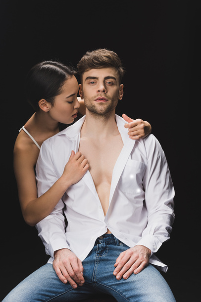 sensual asian woman embracing handsome boyfriend in white shirt isolated on black - Zdjęcie, obraz