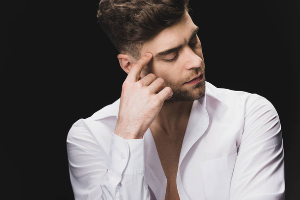 serious handsome man in white shirt holding hand near face isolated on black - Foto, afbeelding