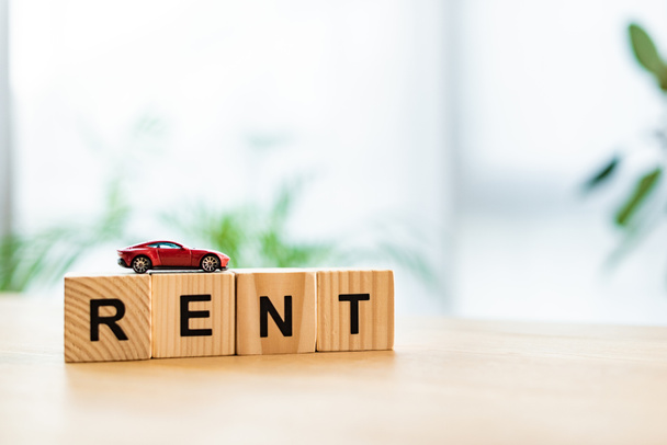 red toy car on wooden cubes with rent lettering on table  - Photo, Image