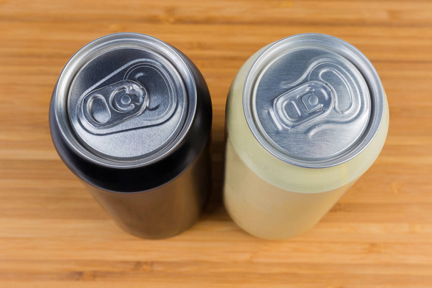 Vista superior de dos latas de bebidas selladas diferentes en la superficie de madera
 - Foto, Imagen