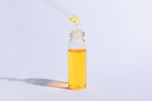 Kosmetik- oder Medizinflasche mit Pipette. Gold flüssiges Produkt in Glasflasche mit Tropfer auf weißem Hintergrund. Schönheitskonzept. Banner - Foto, Bild