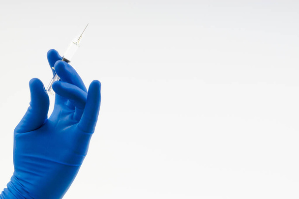 Hand in a blue glove holding syringe isolated on white - Photo, Image