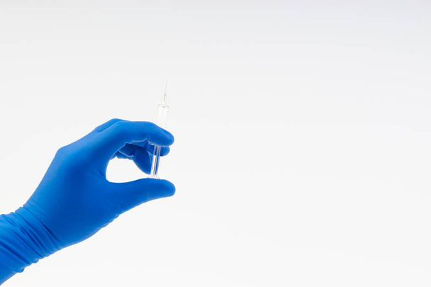 Ruka v modré rukavici s injekční stříkačkou izolovanou na bílé - Fotografie, Obrázek