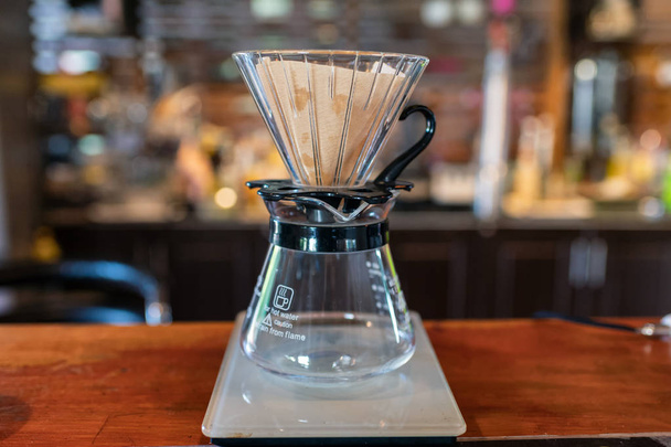 Measuring coffee drip with glass mug and paper filter on counter - Φωτογραφία, εικόνα