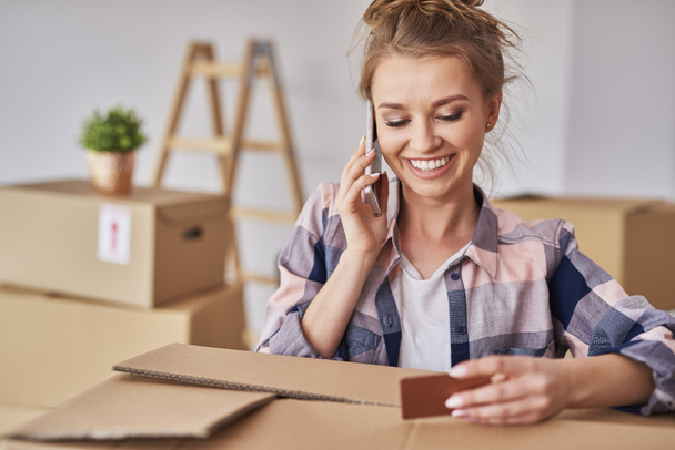 Smiling woman using phone while moving house  - Photo, Image