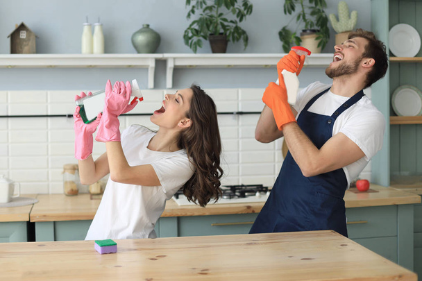 Young happy couple is having fun while doing cleaning at home. - Photo, Image