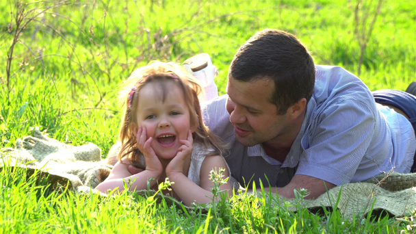Mutlu baba ve kızı çimenlerin üzerinde dinleniyor. - Video, Çekim